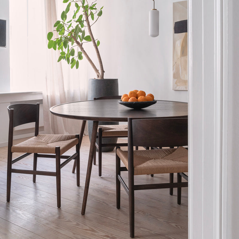 An eco-friendly grey Accent dining table made of FSC-certified wood by Mater, with three Nestor chairs.
