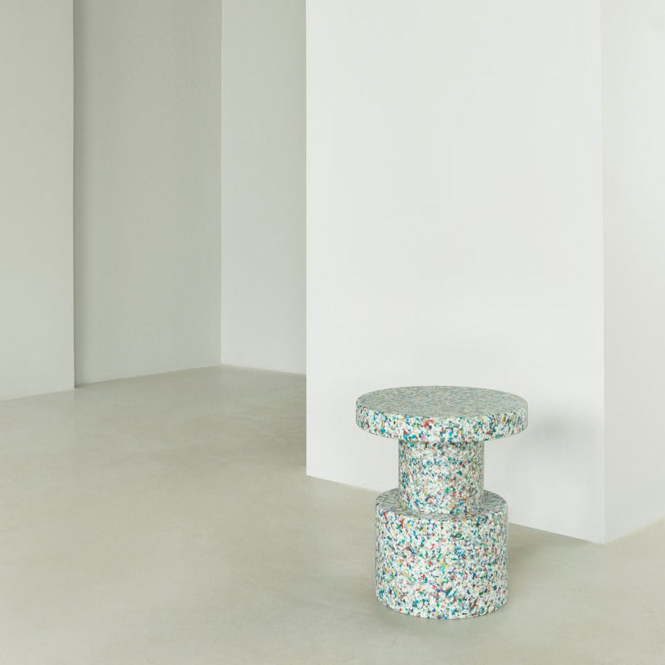 A Bit Stool in White Multicolor, made of recycled plastic by Normann Copenhagen, in a sleek modern living room.