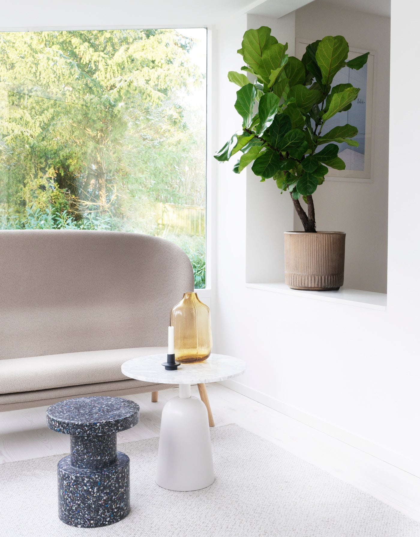 A Bit Stool Stack in Green, made of recycled material by Normann Copenhagen, in a modern living room next to a sofa.