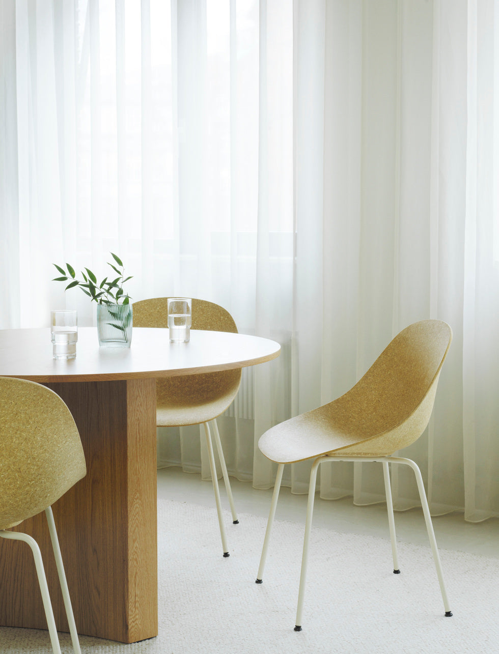 Three renewable Mat Chairs by Normann Copenhagen, with white-coated legs, shown around a light wood dining table.
