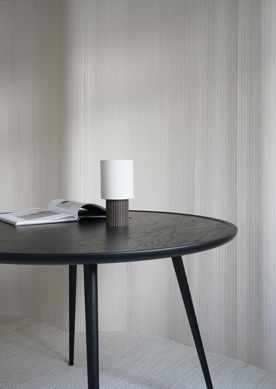 A sustainable black Accent dining table made of FSC-certified wood by Mater, in a living room.