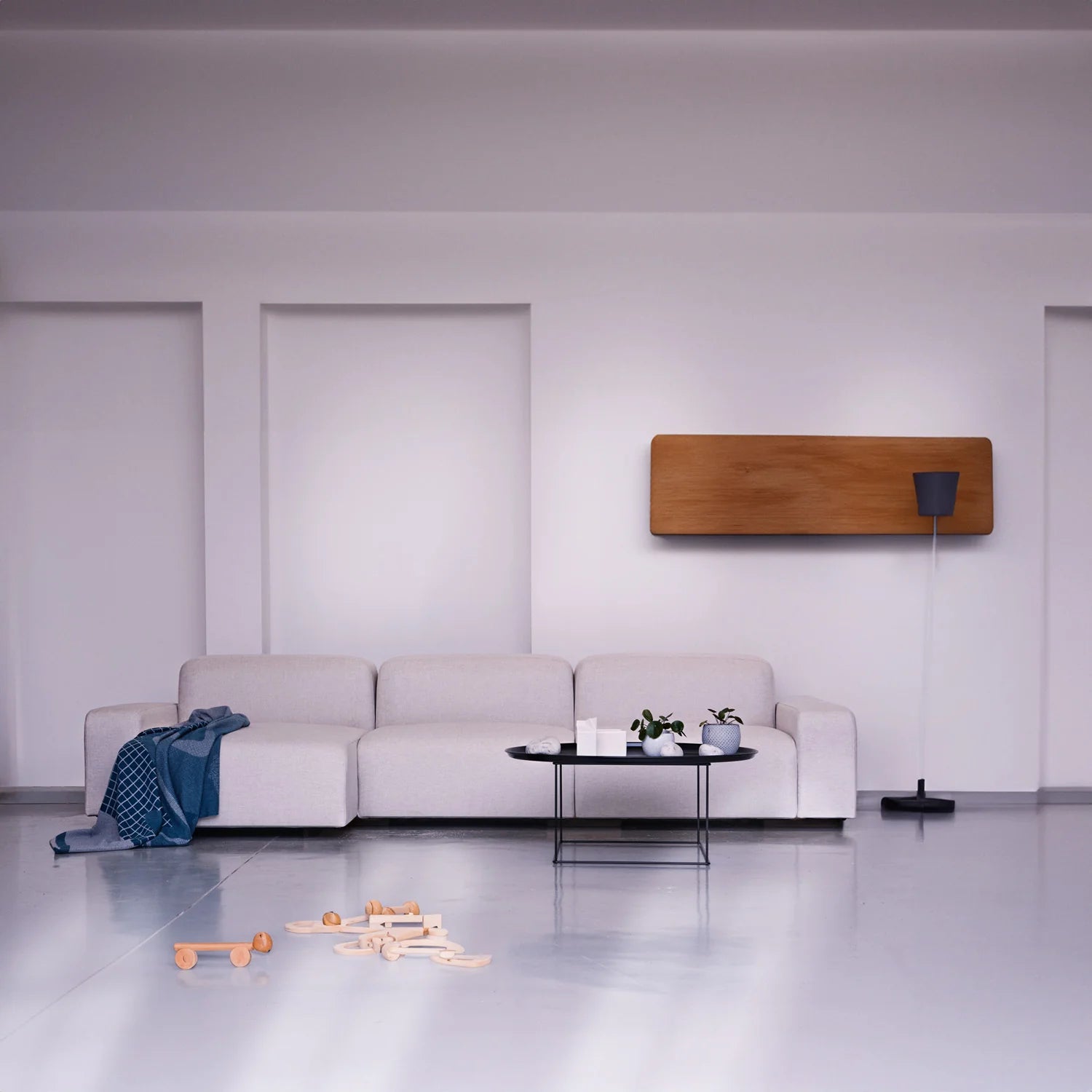 A white sofa with three seats and a chaise, by Biosofa, shown with a lamp and coffee table.