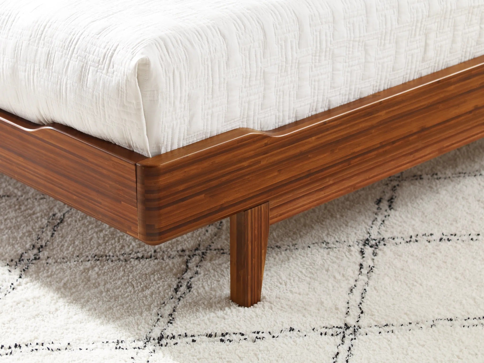 The detail of a renewable Currant Bamboo Bedframe by Greenington, in amber color.