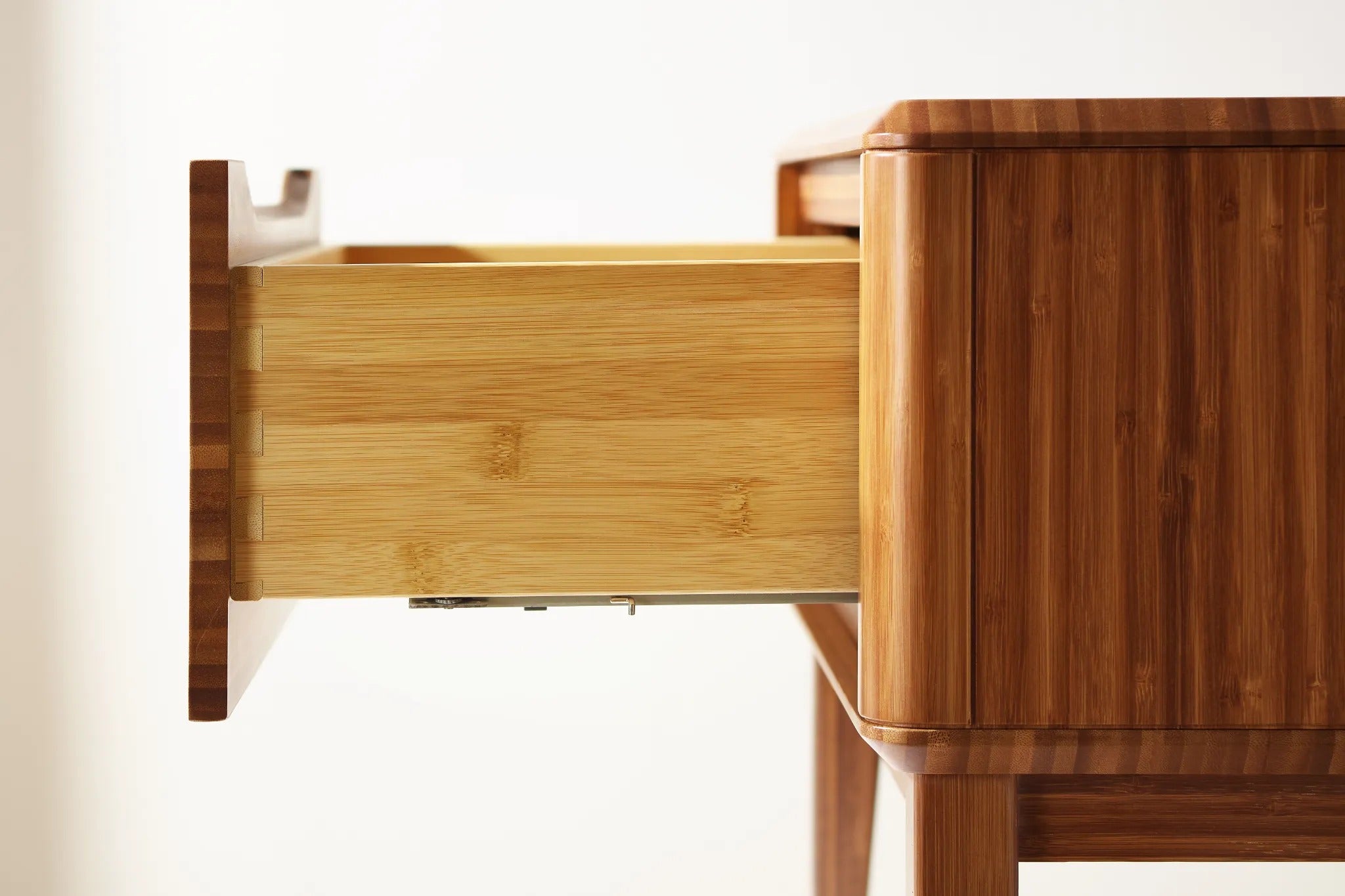 Side detail of the drawer of the renewable Currant Bamboo Nightstand by Greenington, in amber color.