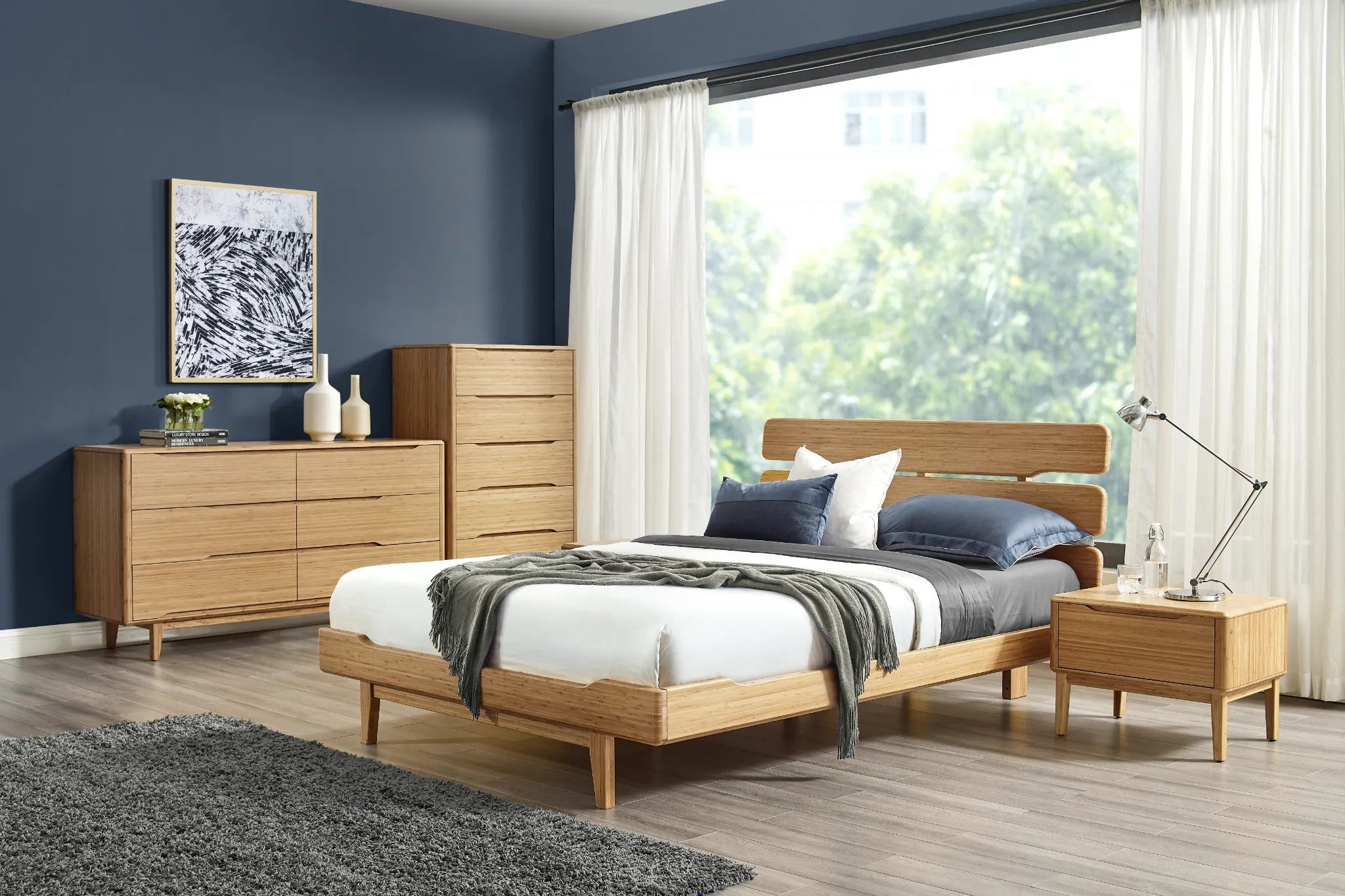 A renewable Currant Bamboo High Dresser by Greenington, in caramel color, placed in a bedroom alongside the bed, a nightstand, and a low dresser.