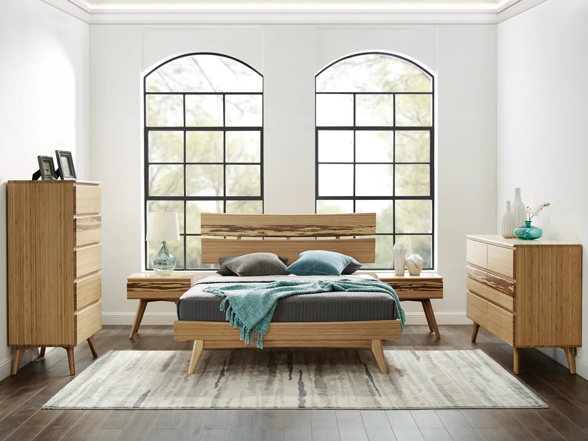 A sustainable Azara Bamboo High Dresser by Greenington, in caramel color, situated in a bedroom alongside a bed, a low dresser, and two nightstands.