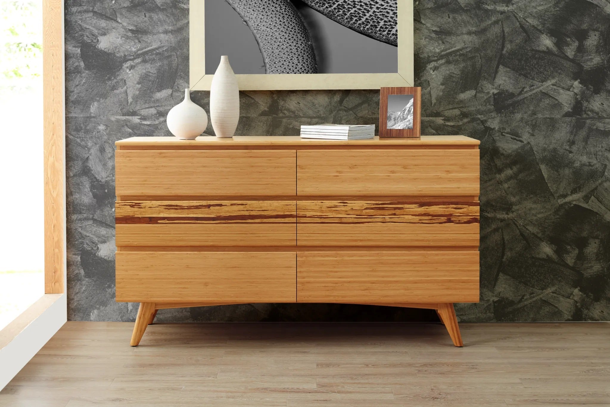 A sustainable Azara Bamboo Low Dresser by Greenington, in caramel color, placed in a living room with a vase and a frame on top of it.