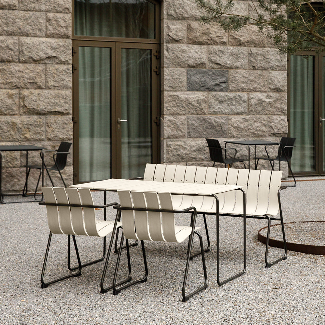 A rectangular Ocean Table made with recycled materials by Mater, in sand color, surrounded by four Ocean Chairs.