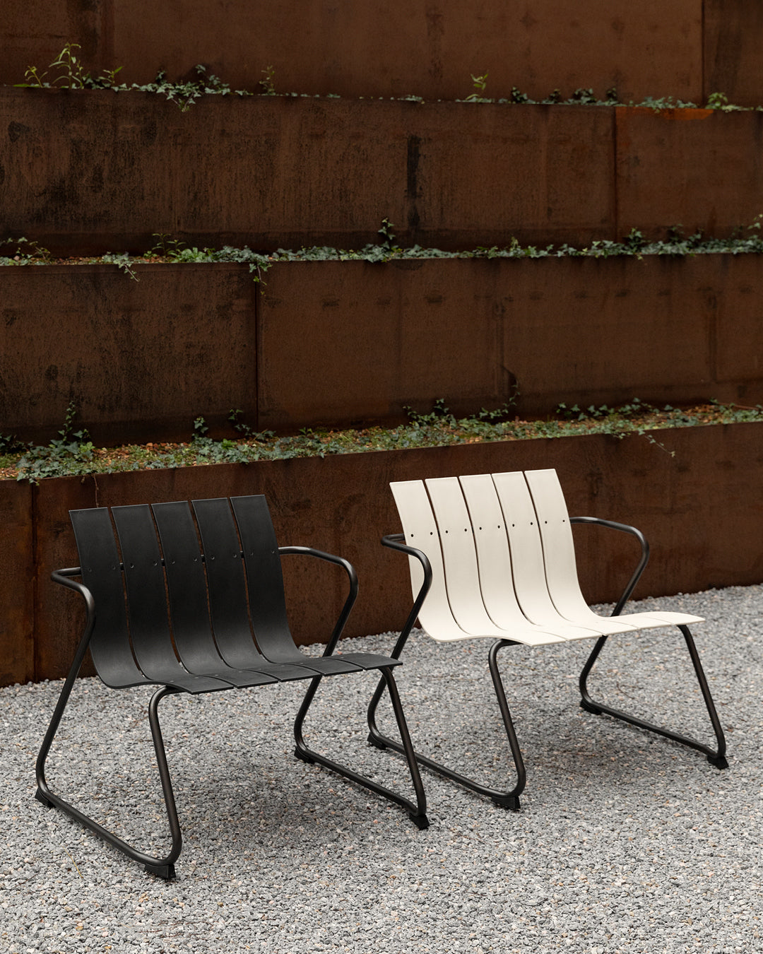 Two Ocean Lounge Chairs made of recycled materials by Mater, in sand and black, placed outdoors.