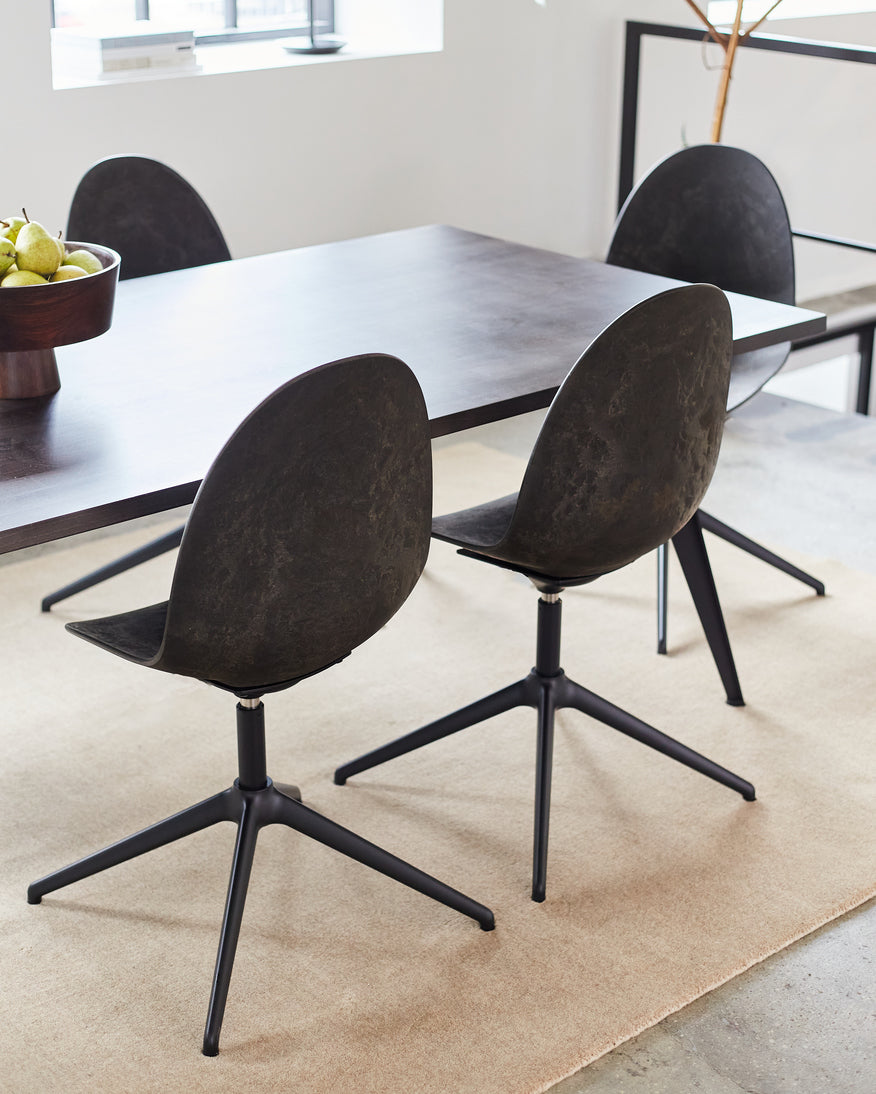 Three Matek Eternity Swivel Chairs made of recycled materials by Mater, in black, placed around a dining table.