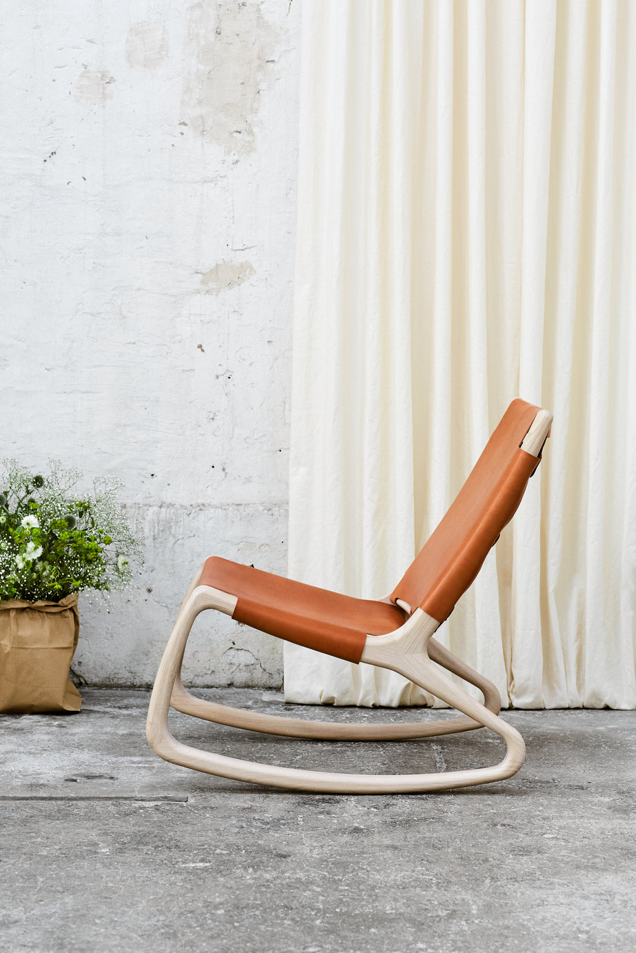 A tan leather Modern Rocker Chair made of FSC-certified wood by Mater, side view.