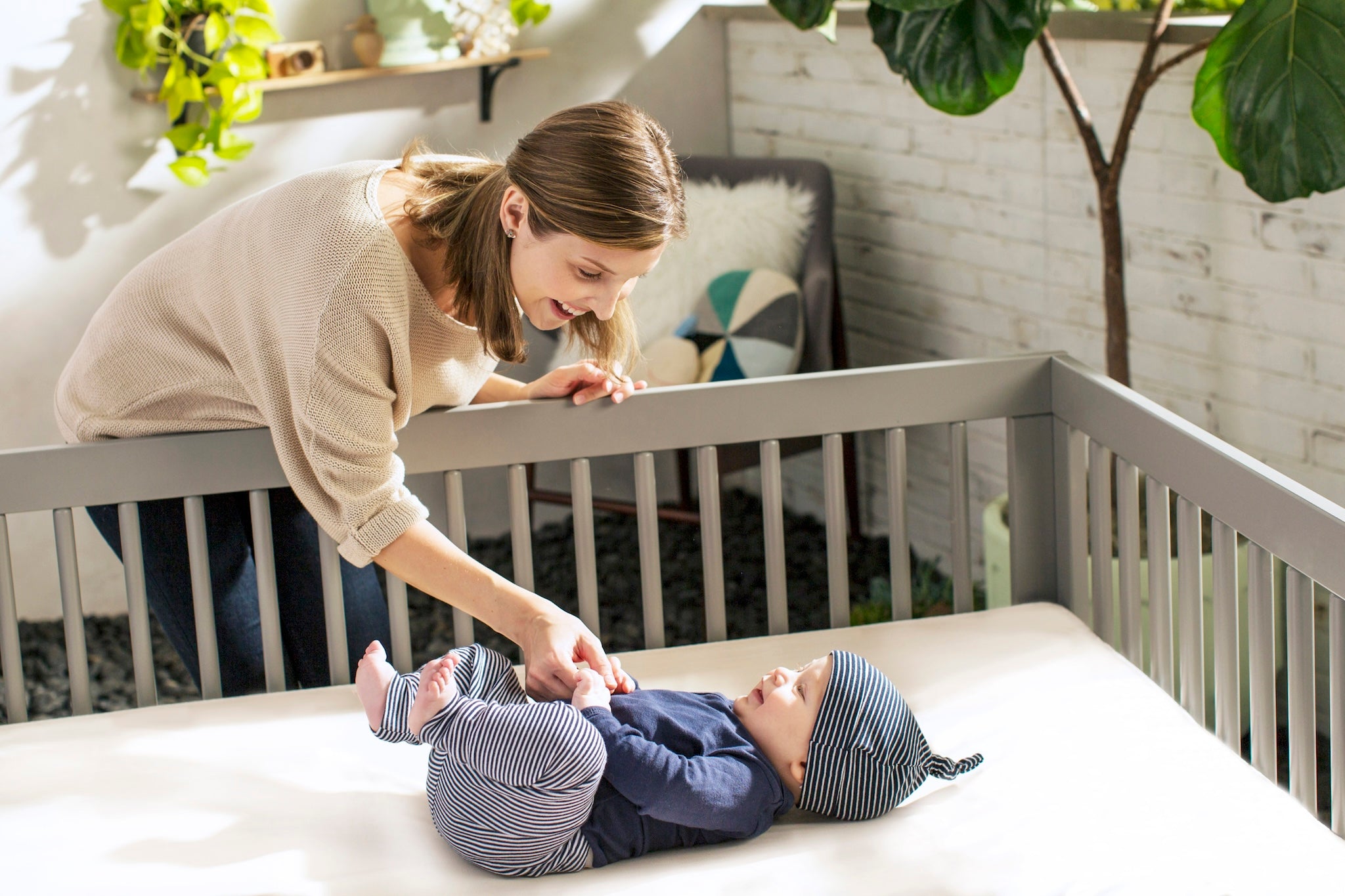 Woman interacting with a baby in a crib in a home setting