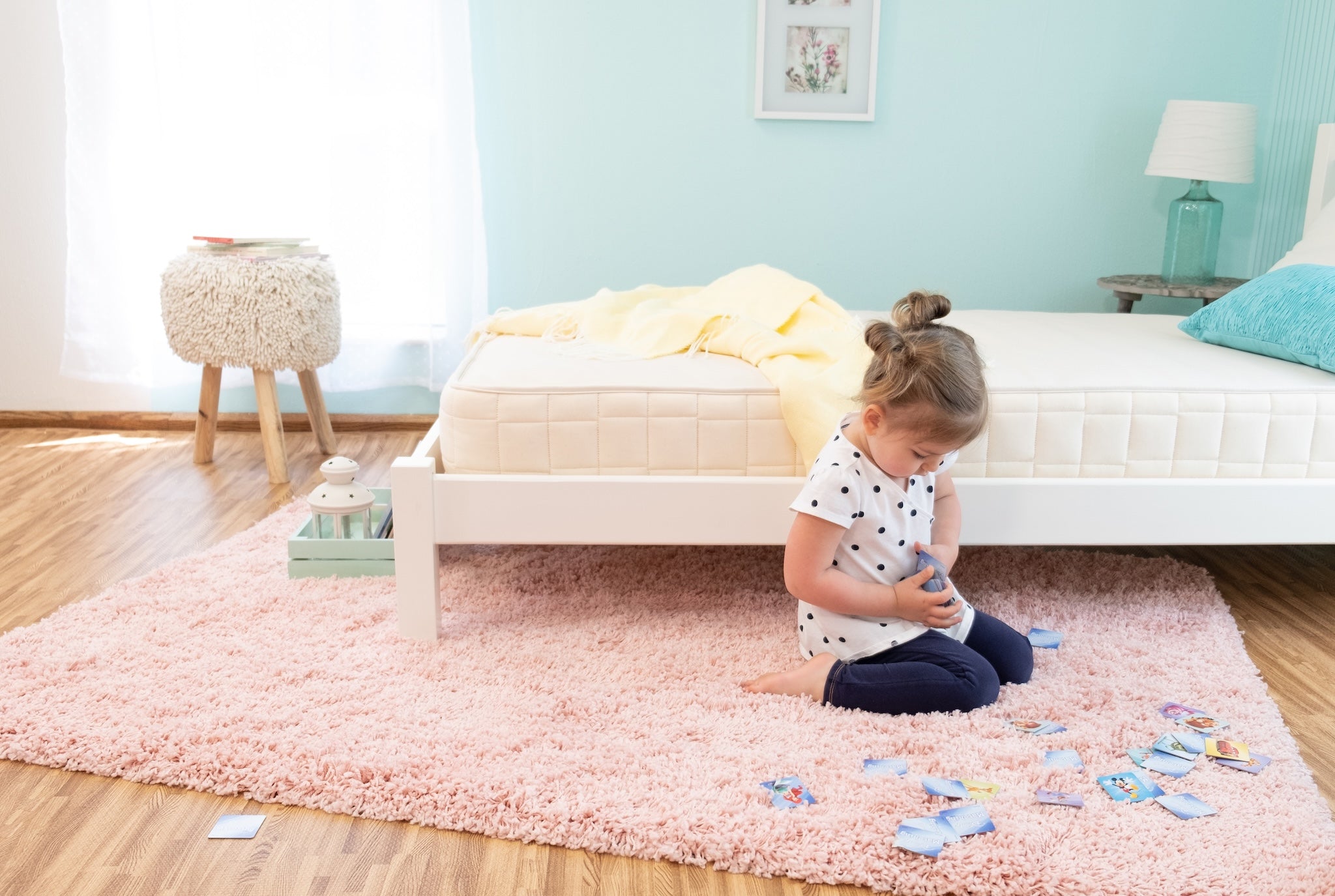 Child playing with toys on a pink rug in a bedroom