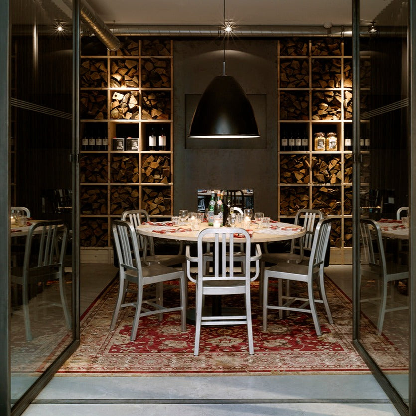 A dining table with six Navy Chairs and Armchairs by Emeco, inside the Mazzo Restaurant in Amsterdam.