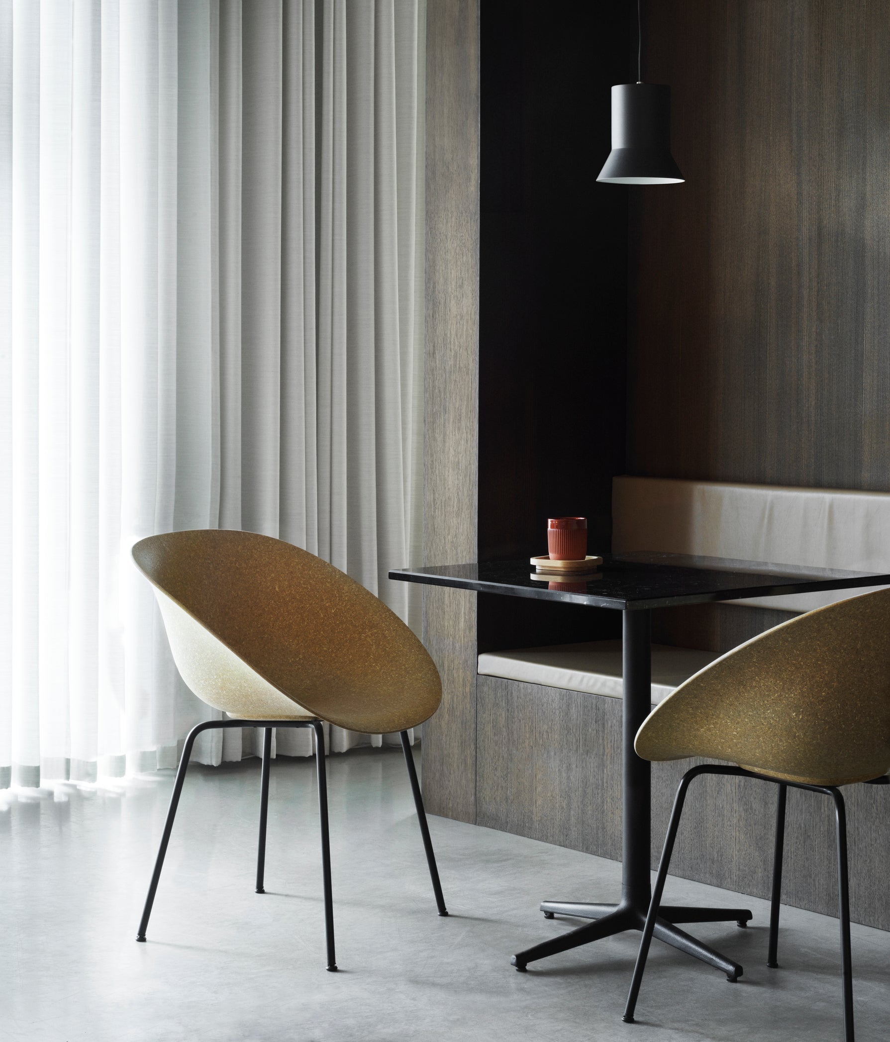 Two renewable Mat Armchairs made with hemp plants by Normann Copenhagen, with black-coated legs, placed around a table.