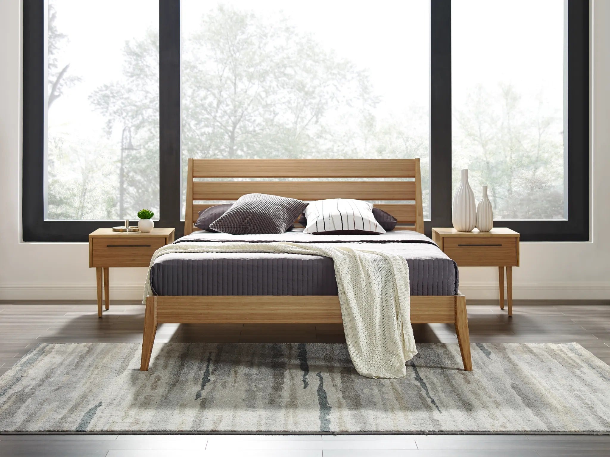 Two eco-friendly Sienna Bamboo Nightstands by Greenington, placed in a bedroom alongside a bed.