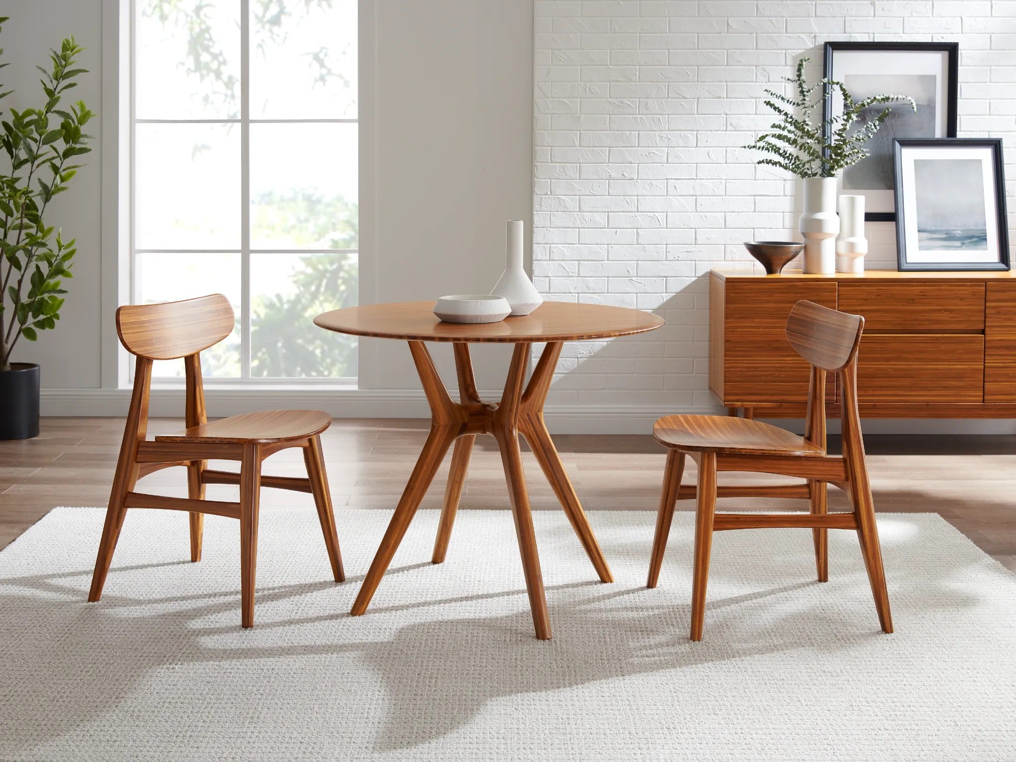An eco-friendly Sitka Bamboo Dining Table by Greenington, in amber color, together with two bamboo chairs in a living room.
