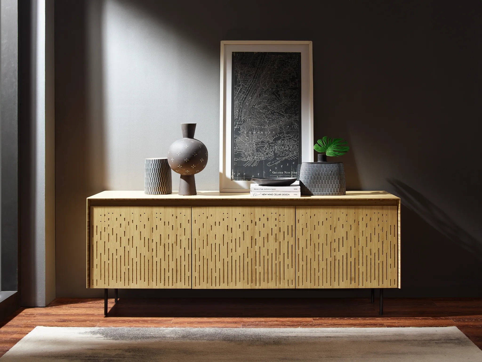 A sustainable Hanna Bamboo Sideboard by Greenington, with vases and an elegant art work against a grey wall.