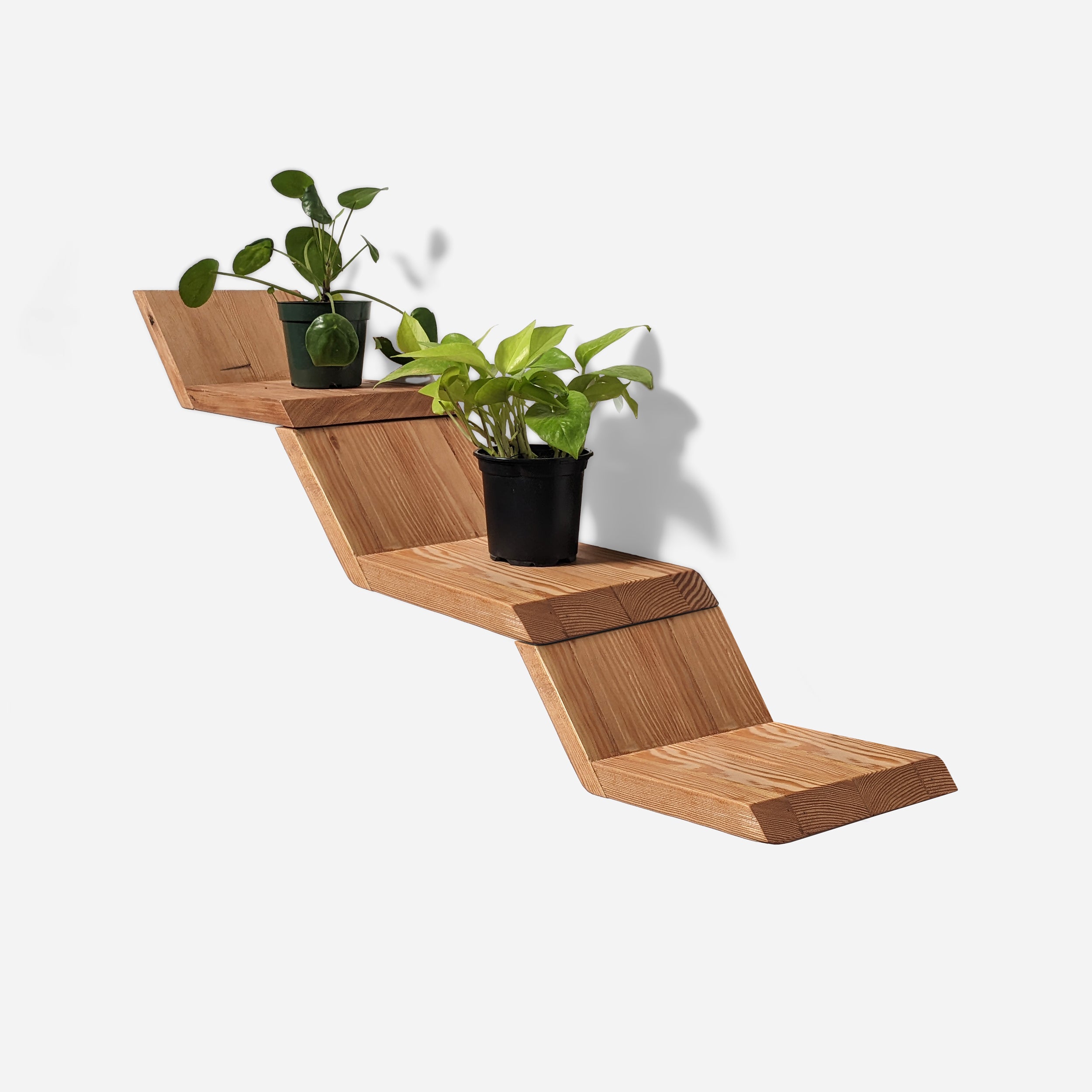 A three-layered wall-mounted Lean Shelf by Formr in wood finish, with two potted plants.