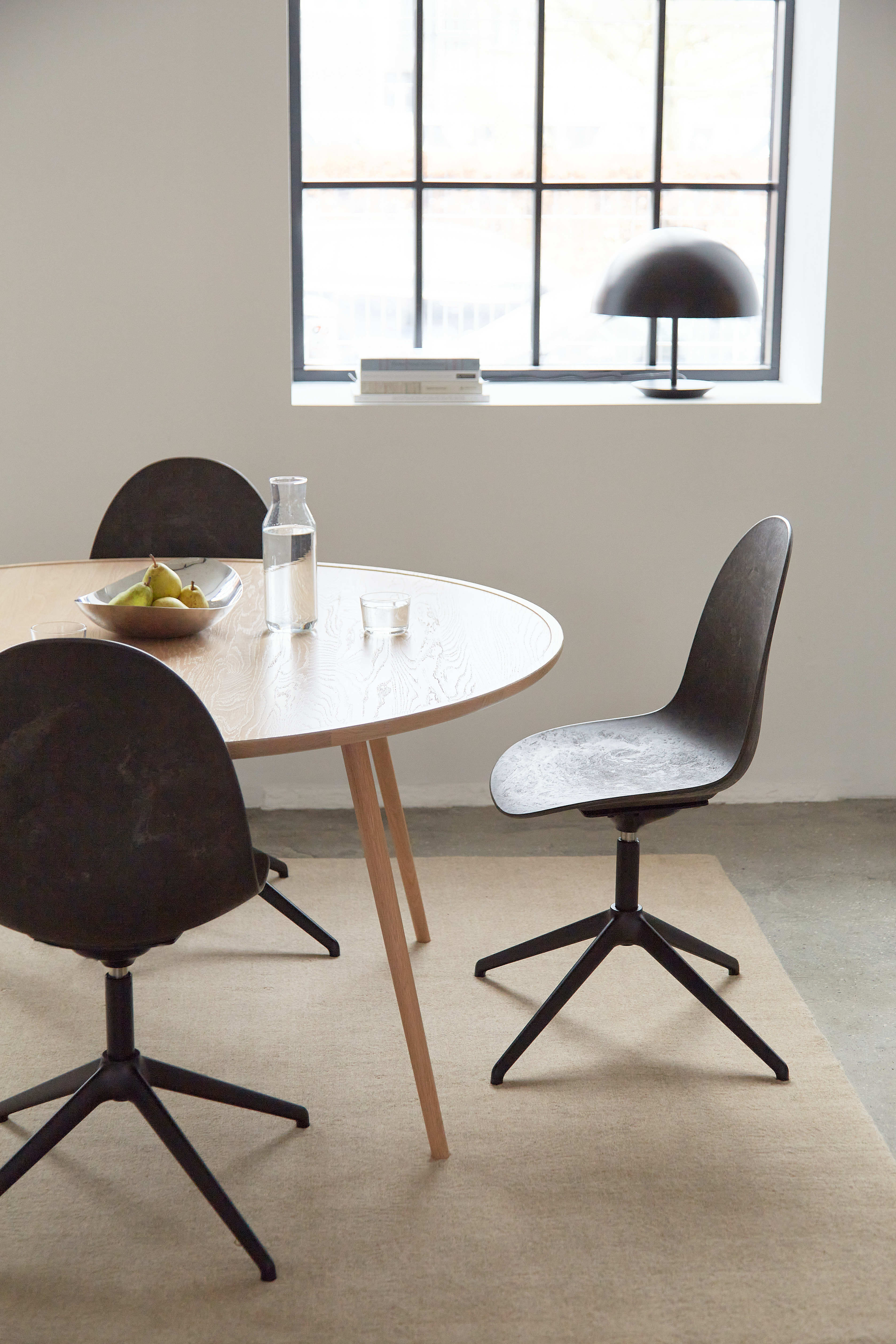 Three Matek Eternity Swivel Chairs made of recycled materials by Mater, in black, placed around a dining table.