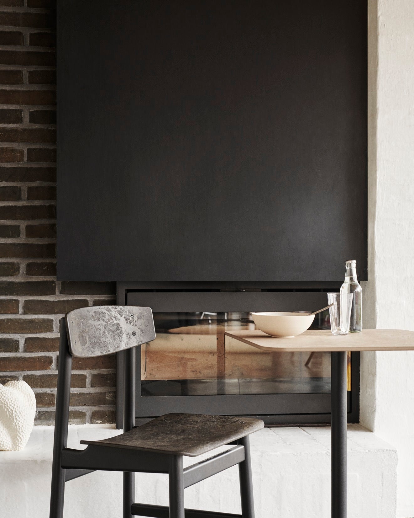 A sustainable table with a black Conscious chair made with recycled material, by Mater.