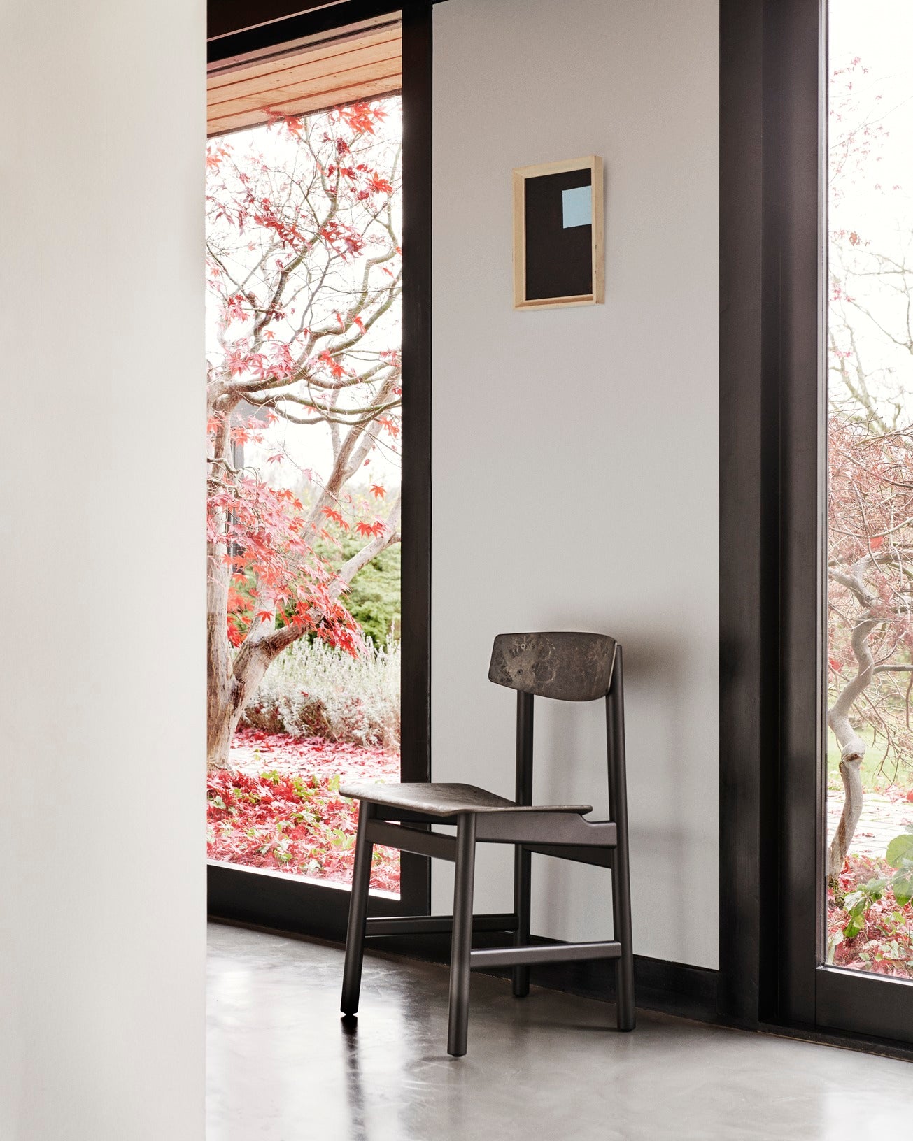 A black Conscious chair made with recycled material by Mater, near a large window.
