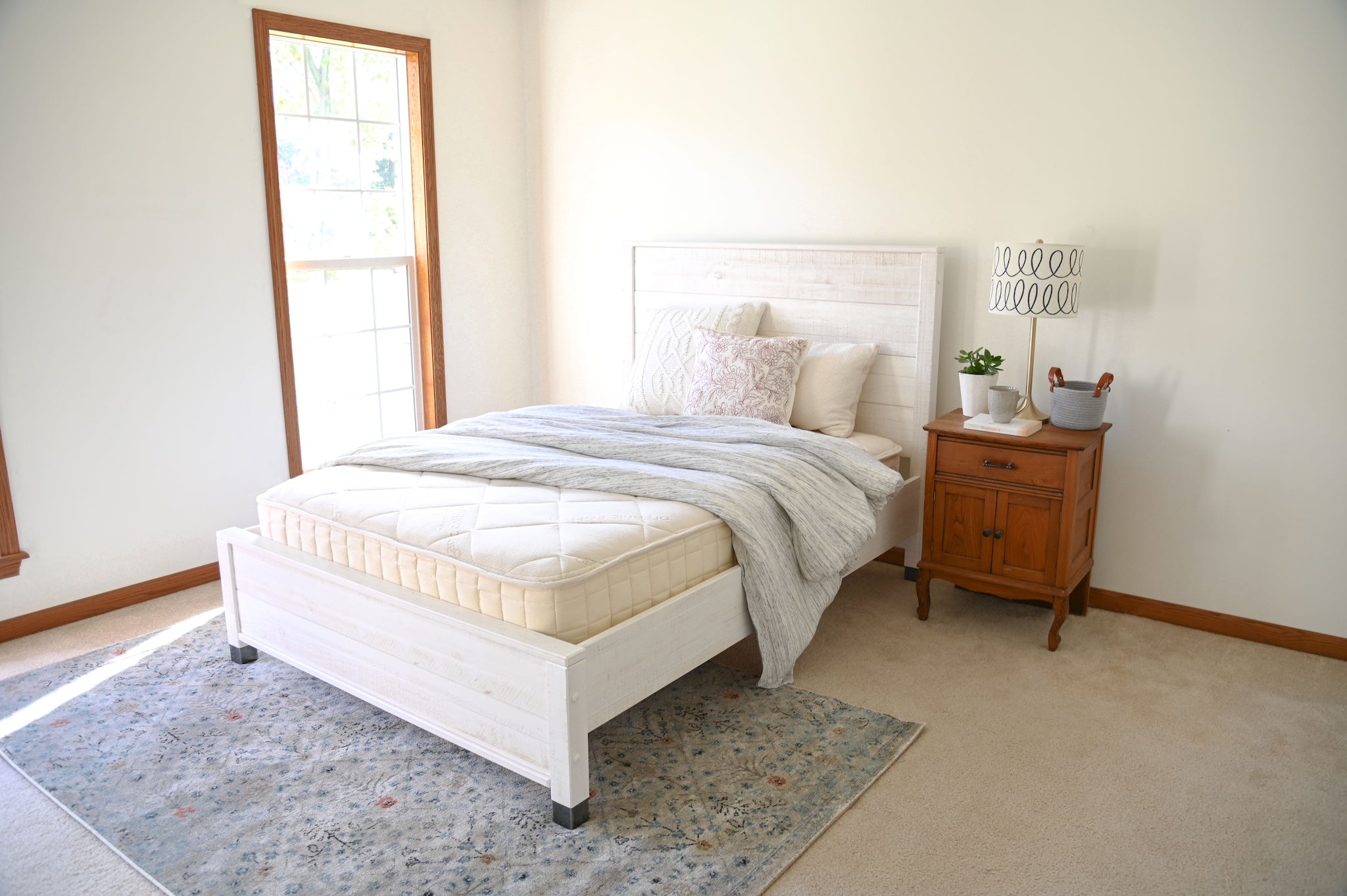 Bedroom with a bed, nightstand, and lamp in a well-lit room.