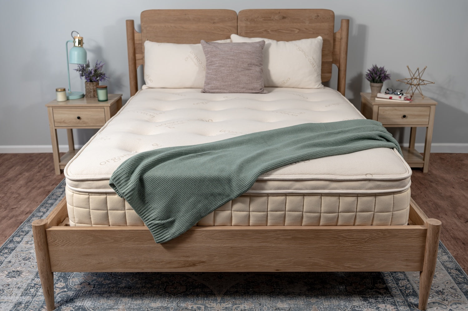 Bed with wooden frame and organic mattress in a room setting with blanket