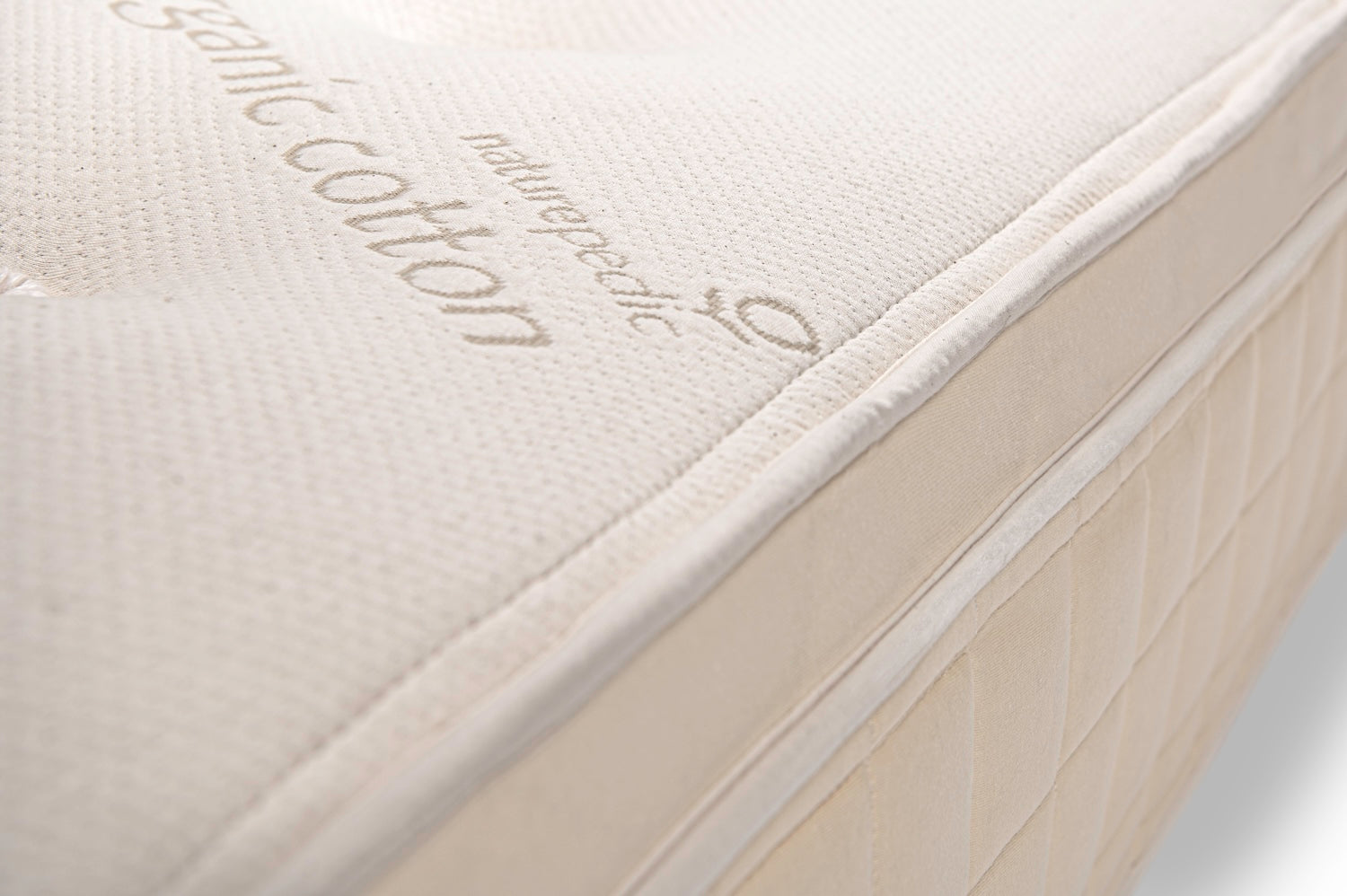 Close-up of a mattress with 'organic cotton' embroidery on a white background