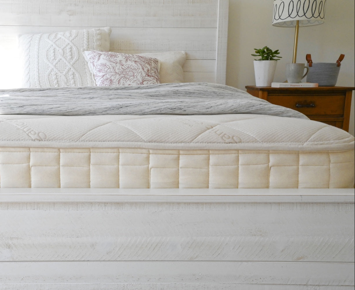 White mattress with pillows on a bed in a bedroom setting
